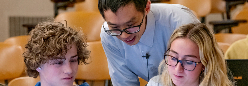 Banner Image: Photo of Professor helping students in a classroom